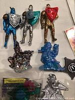 Three Laser Knights action figures in blue, silver, and gold armor with shields, metallic dragon and blue dinosaur finger board toys
