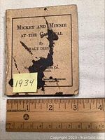 Front cover of the small booklet titled 'Mickey and Minnie at the Carnival' with visible ink stains and a ruler showing size.