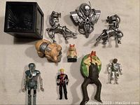Overview photo showing all Star Wars and related figures including Darth Vader in cube, Yoda, Medical Droid, Daggit robot, Jar Jar Binks wind-up, and other metallic figures