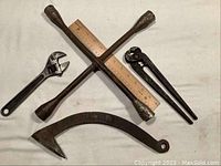 Front view of the cross-style lug nut wrench, log roller hook, and wrench types on white cloth.