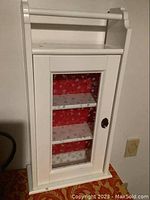 Front and side angle showing the white cabinet with glass door and towel bar on top