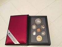Closed red satin cover with Royal Canadian Mint branding and coins visible in black holder inside.
