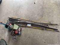 Four fishing rods laid on the floor with a tackle box.