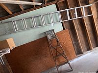 Aluminum extension ladder hanging horizontally on a wall, showing full length and condition.