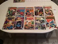 Top view of all 10 Marvel comic books laid out on a white folding table, each individually sleeved in clear plastic.