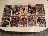 Photo showing the full set of 10 Marvel comics in plastic sleeves on a white table.