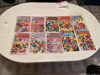 Overview of ten Marvel comics in plastic sleeves arranged on a table, including Marvel Universe Official Handbooks and Secret Wars issues.