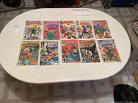 Overview photo of ten Marvel comic books laid out on a table in plastic sleeves showing series including Secret Wars and Fantastic Four