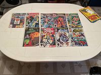 Lot of 9 Marvel comic books displayed on a plastic folding table, each in clear plastic sleeves.