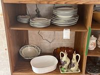 Set of stacked plates and bowls on wooden shelves.