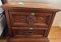 Full view of one wooden side table showing design, drawer hardware, and finish.