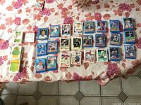 Baseball sports cards spread out on a floral tablecloth background with some cards stacked and some alone.
