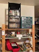 Overview of lot on wooden shelving including the black 3-drawer storage organizer, turquoise multi-drawer organizer, and various tools and hardware items.