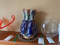 Front view of blue ceramic vase showing floral decorative pattern and scalloped top rim.