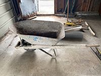 Full side view of the large metal wheelbarrow showing basin, handles, and wheel.