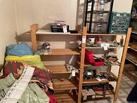 Wooden shelf unit in basement with various items on and around it (contents not included). Five slatted shelves visible, natural wood finish.