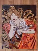 Full view of the front side of the glazed wall plaque showing the woman and bicycle in vibrant orange, brown, and gold colors.