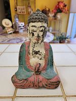 Front view of the carved and painted Buddha statuette showing detailed facial features and paint wear.