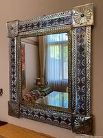 Full front view of rectangular mirror with metal and tile frame hung on wall