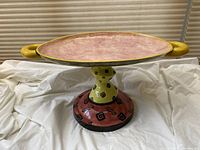 Full view of the ceramic centrepiece, showing base, pedestal, and handles with vibrant glaze colors.