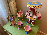 Full view of the two-tier scone tray, two teacups, rabbit figurine, and dog-shaped pot on green surface