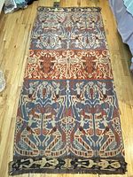 Full view of the handwoven textile laid flat on the floor showing the full pattern and color scheme.