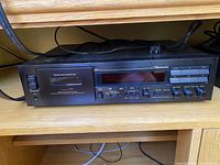 Full front view of black Nakamichi DR-1 cassette deck on wooden shelf