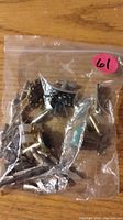Clear small plastic bag containing multiple assorted metallic tie tacs and cuff links.