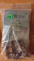 Plastic bag of assorted jewelry pieces from seller's grab bag lot. Appears to include rings, clip-on earrings, and small jewelry items in mixed metal tones and colors.
