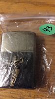 Photo of metal Zippo lighter with raised golf player design on front, showing wear and patina.