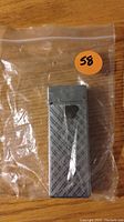 Photo of a grey plastic butane lighter in a clear plastic bag with an orange sticker marked '58' on the top right corner.