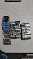 Photo of assorted chrome sockets, some in packaging, laid out on white surface