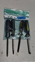 Photo showing a set of four assorted screwdrivers in a zip-lock bag, varying in handle style and showing signs of use.