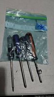 Four screwdrivers of various handles and sizes packed inside a plastic resealable bag.