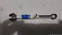 Photo of two metal wrenches on a surface, one combination wrench and one double open-ended wrench with blue and white tape on the handle.