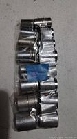 Single photo showing a set of 13 miscellaneous metal sockets of various sizes held in a plastic strip.