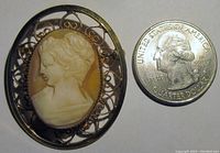 Close-up of the Catamore shell cameo brooch next to a US quarter for size reference.