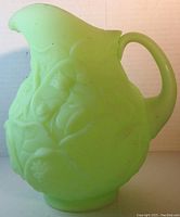 Front and left angled view showing the embossed water lily satin uranium glass pitcher shape and handle