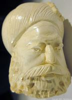 Close-up of the carved meerschaum pipe bowl showing the detailed facial features of the bearded man