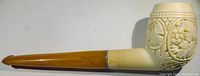 Side photo showing the pipe from the left side, detail of the carved grapevine design on the meerschaum bowl and amber-colored stem.