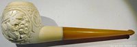 Side view of the full meerschaum pipe showing the carved bowl and amber stem