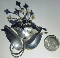 Large sterling silver floral brooch shown with U.S. half dollar coin for size comparison, showing petal shapes and rhinestone clusters.