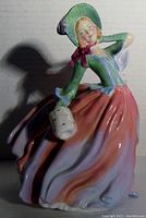 Side view of Royal Doulton Autumn Breezes figurine showing flowing skirt and basket detail.