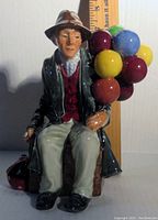 Front view of the Royal Doulton Balloon Man figurine showing the seated figure holding colorful balloons, detailed facial expression and clothing.