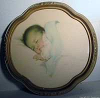 Front view of the vintage print showing a sleeping baby with wings in a sculpted frame.