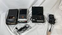 Three vintage Sony tape players and recorders shown side by side on white backdrop.