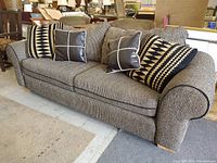 Front angled view of Ashley Furniture striped fabric sofa with four decorative throw pillows.