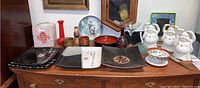 Photo showing four Asian inspired ceramic plates, decorative ceramic ginger jar, plastic red vase, wooden figurine and cup, pottery cup, martini glass and flower vase, and Buddha face rubber planters