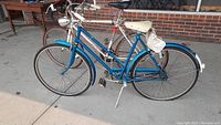 Photo showing the women's 21" FleetWing bike in blue with white saddle and rear bag, featuring upright handlebars and metal fenders.