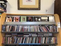 Shelves filled with rows of CDs, some with visible cover art featuring portraits and album graphics.